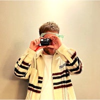 a man wearing glasses and a black shirt in front of a yellow wall